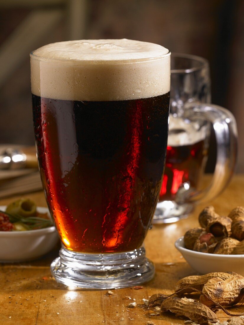 Glass of Dark Beer on a Table with Nuts and Olives