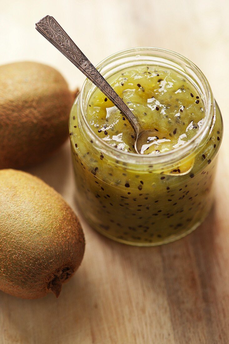 A jar of kiwi jam with fresh kiwis