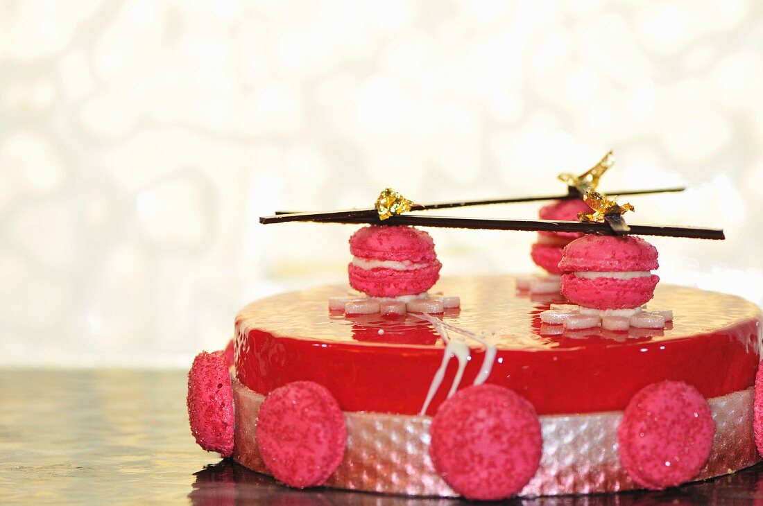 Raspberry cake topped with macaroons and gold leaf