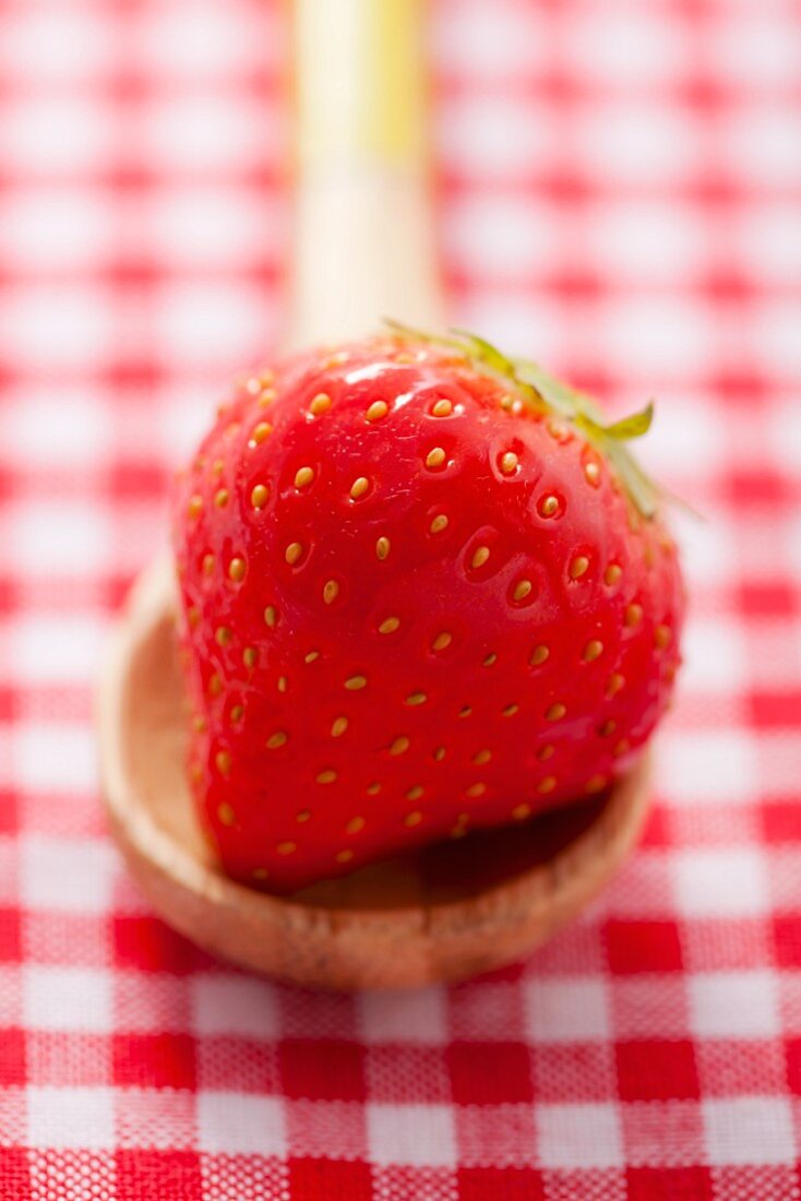 A strawberry on a wooden spoon