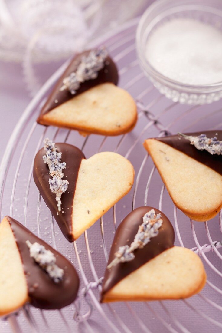 Heart-shaped biscuits decorated with chocolate icing and candied lavender flowers