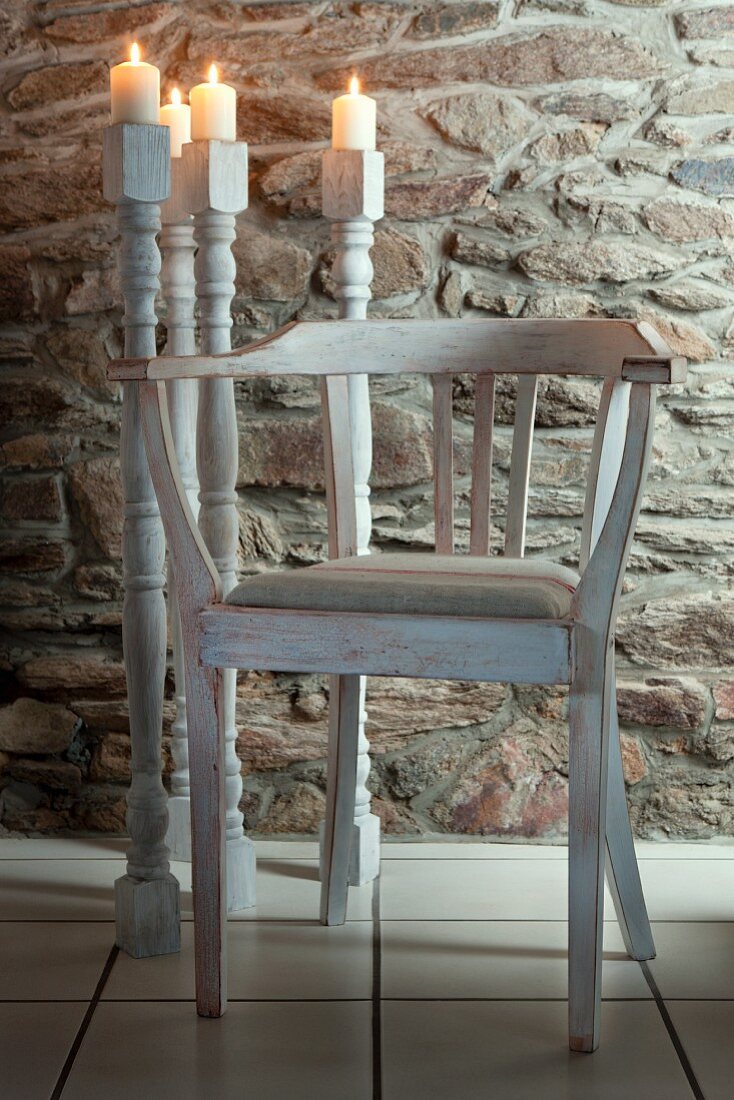 Candlesticks made of old table legs and chair against stone wall