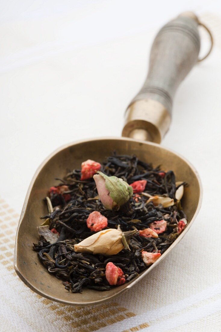 Alte Teeschaufel mit grünem Tee (Sencha) und getrockneten Rosenblüten