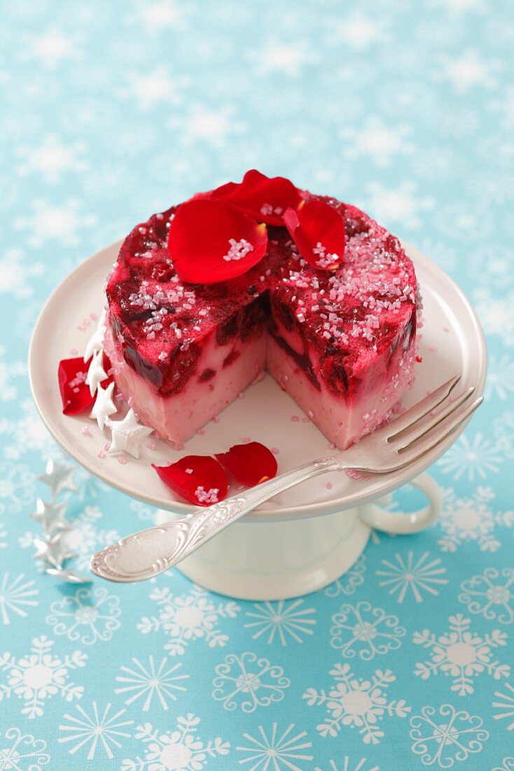 A small cheese cake with cherries and rose petals, sliced