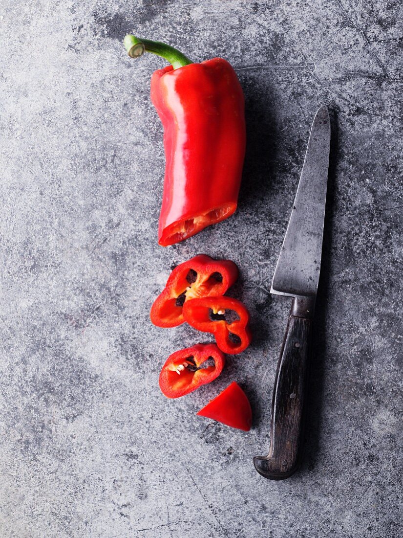 A red chilli pepper, sliced, with a knife
