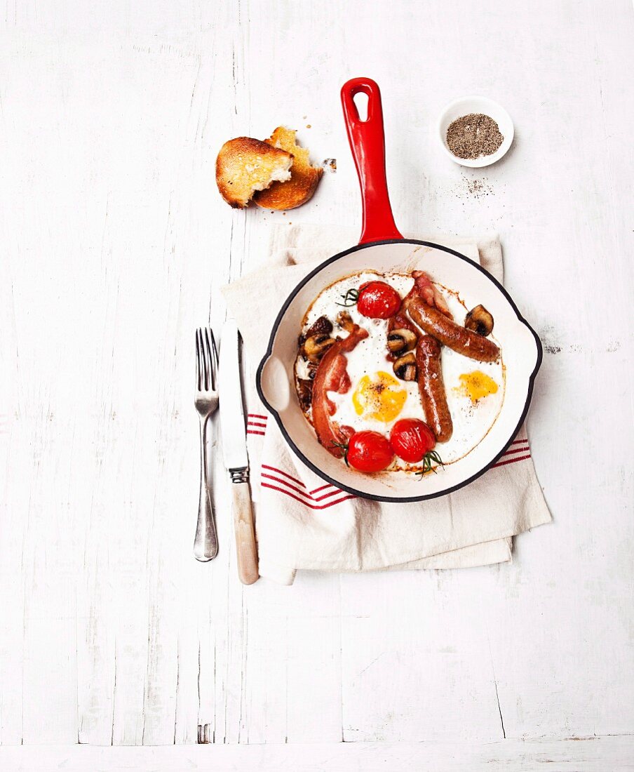English breakfast in a pan (fried egg with sausage and tomatoes)