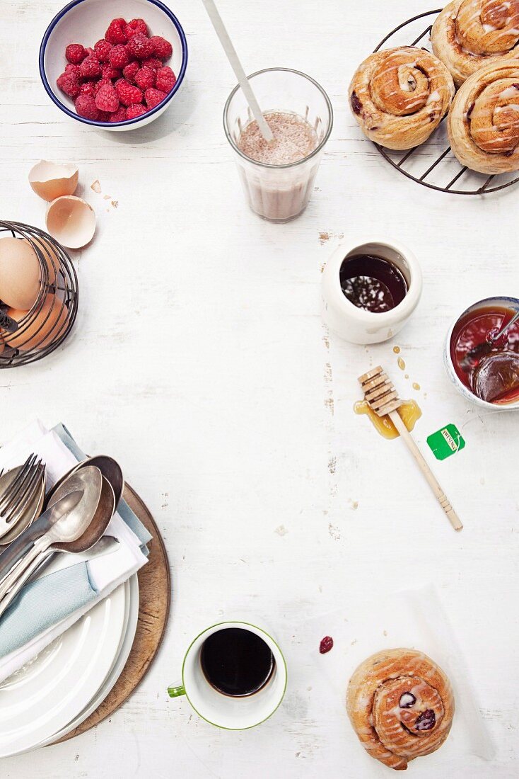 A breakfast table laid with pastries, coffee, eggs and raspberries