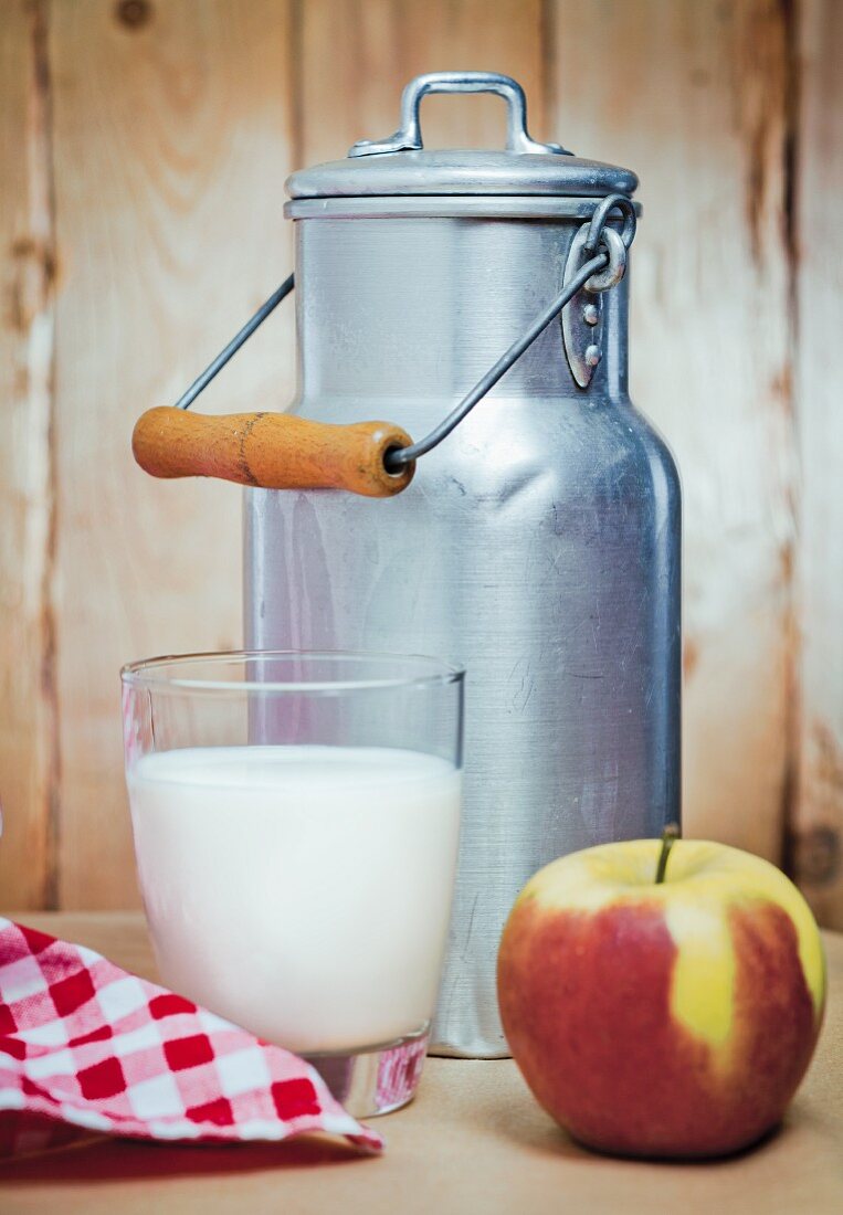 A milk churn, a glass of milk and an apple