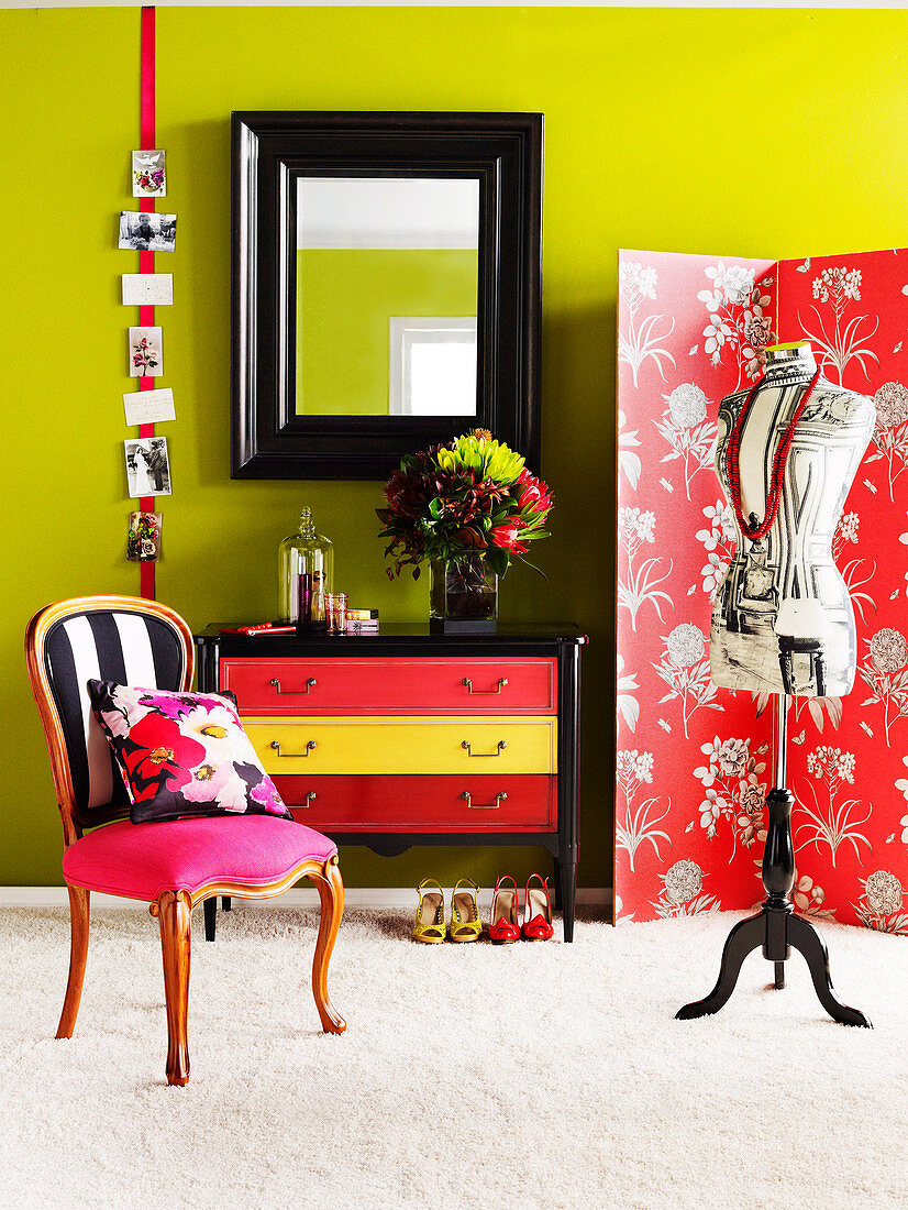 Tailor's dummy in front of screen, mirror with wooden frame and upholstered chair in bedroom with spring green wall