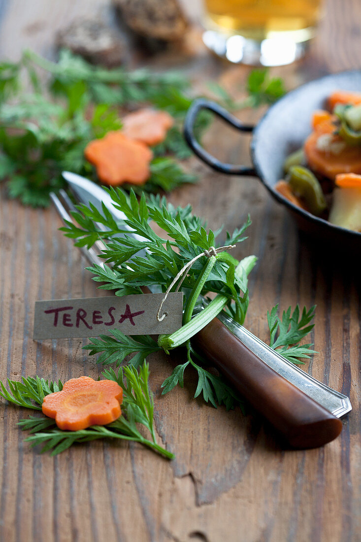 Cutlery tied with carrot stalks and decorated with a place card