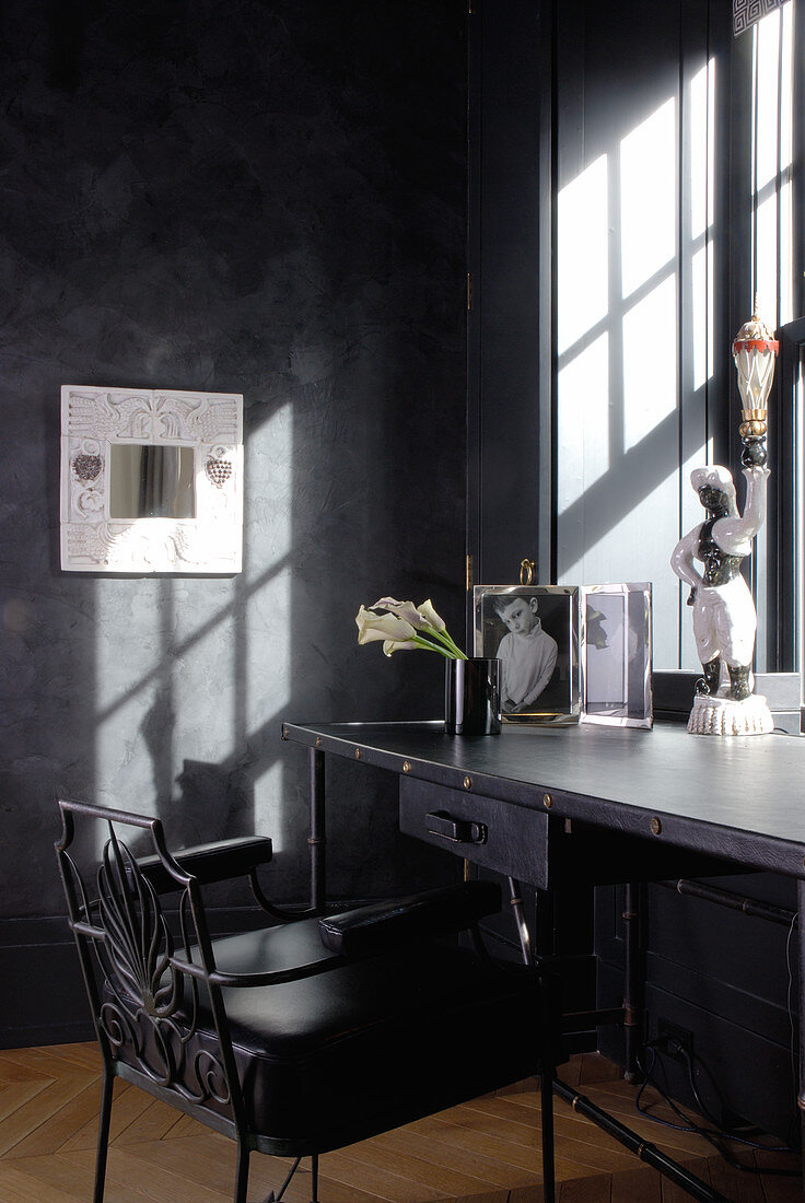 Anthrazitfarbene Schreibtisch-Ecke mit postmoderner Ausstattung am sonnigen Fenster