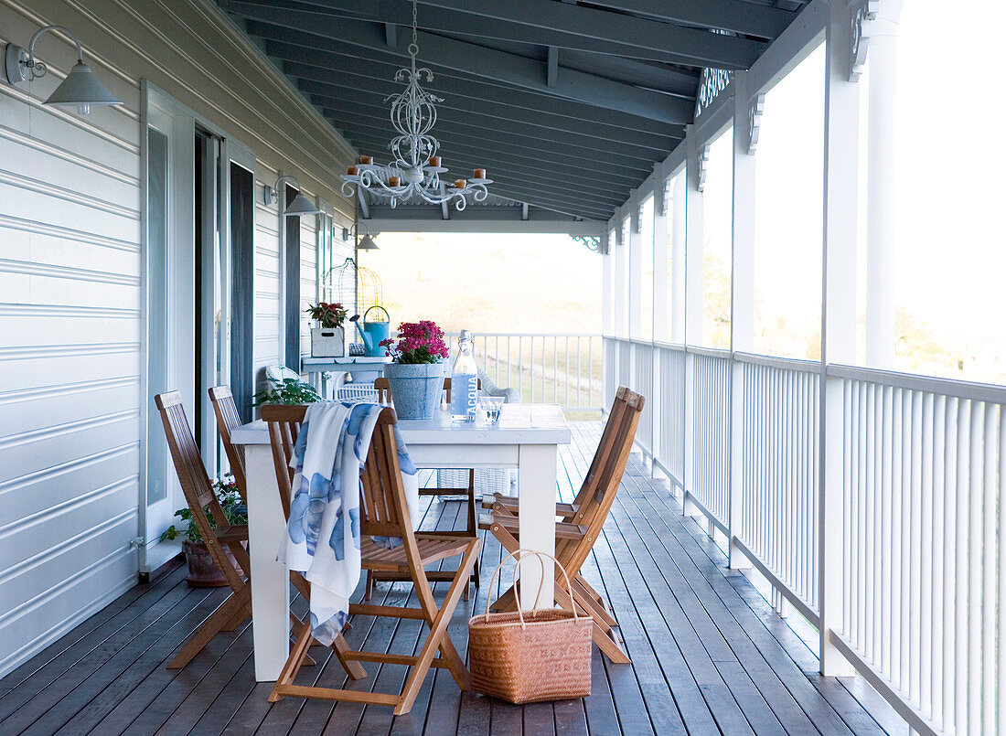 Schlichter Tisch und Stühle auf Veranda eines ländlichen Holzhauses