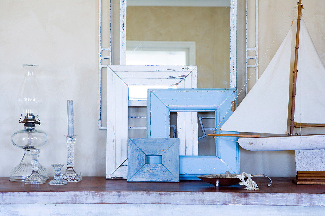 Assorted picture frames next to a model ship on a shelf