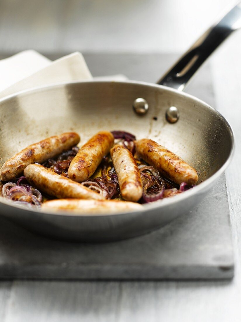 Bratwürstchen mit Zwiebeln in der Pfanne