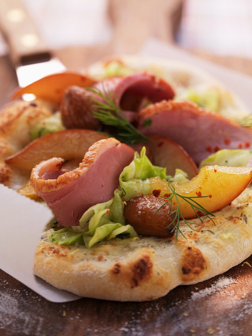 Tarte flambée topped with goose breast, chestnuts, white cabbage and sliced pears