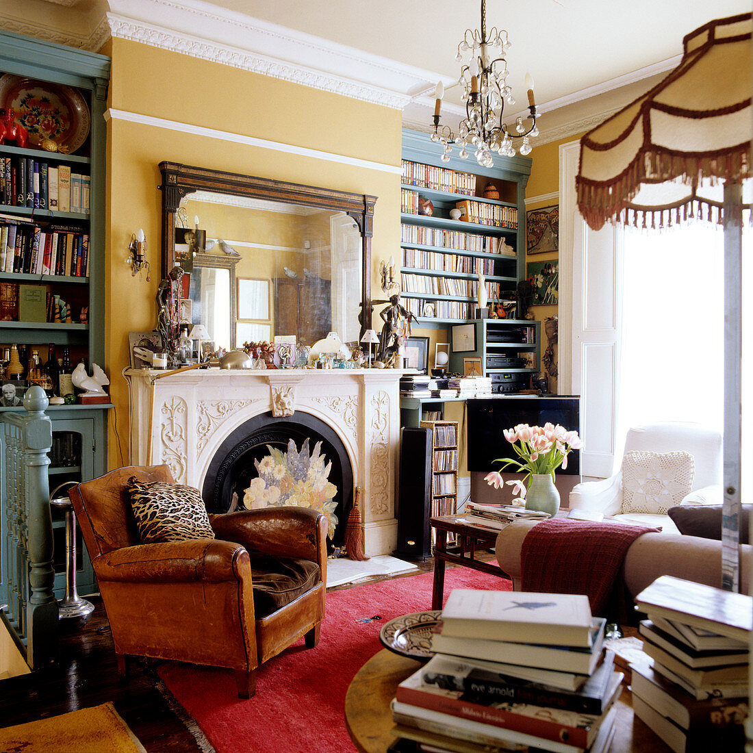 Jugendstil Salon mit Vintage Ledersessel am Kamin und Bücherregale an gelb getönter Wand