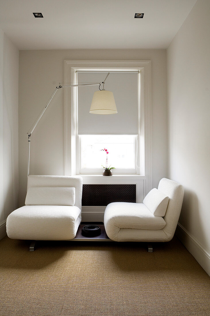 Small, elegant guest room with folding armchair elements and designer lamp by Artemide