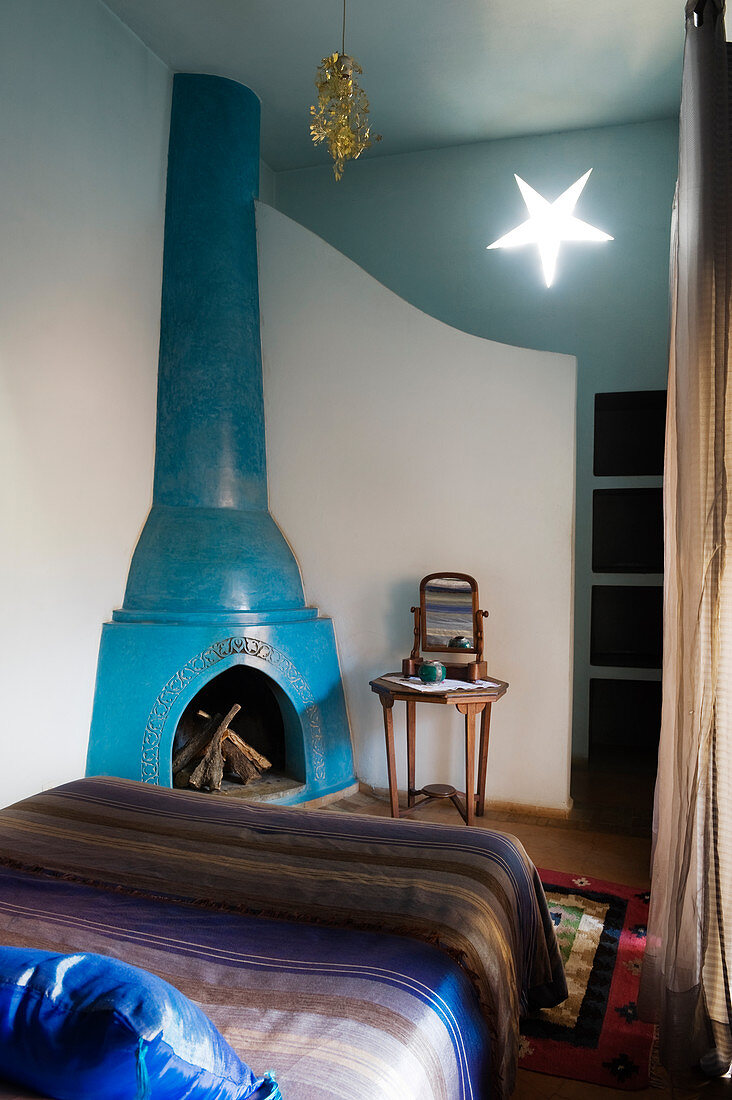 Moroccan bedroom with blue-painted corner fireplace and star-shaped wall lamp
