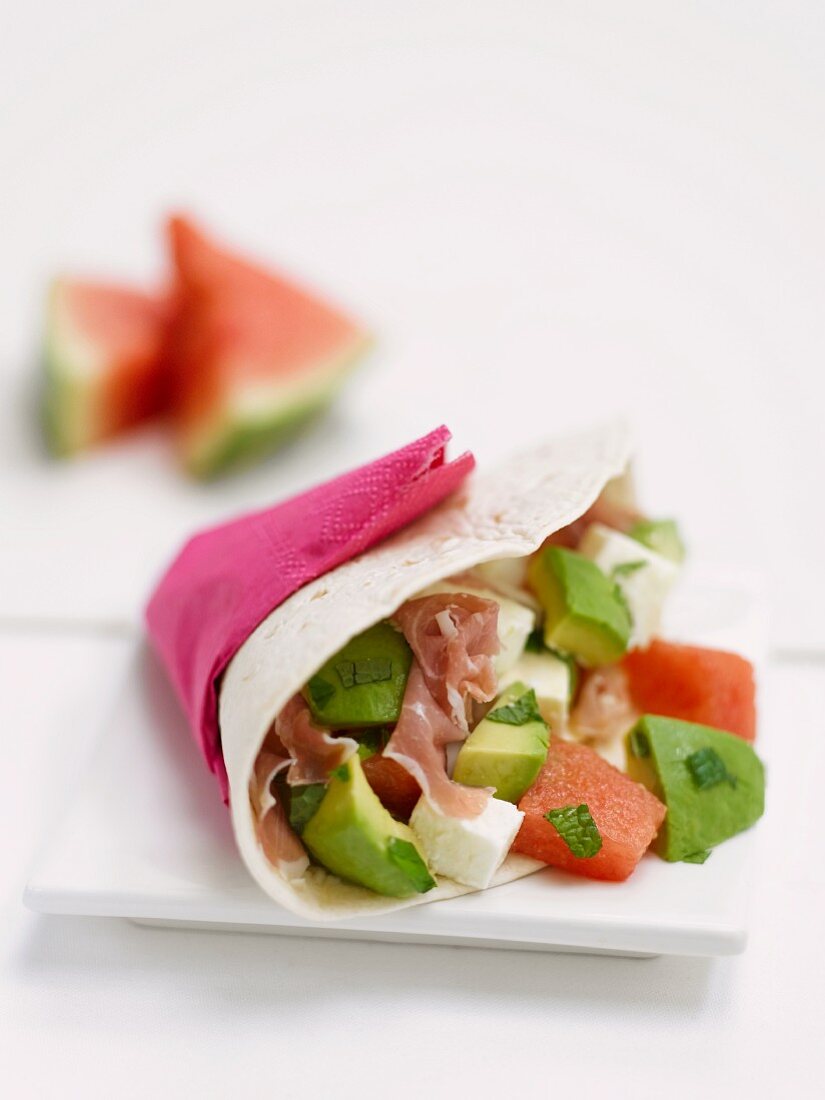 A wrap filled with avocado, Prosciutto ham and watermelon