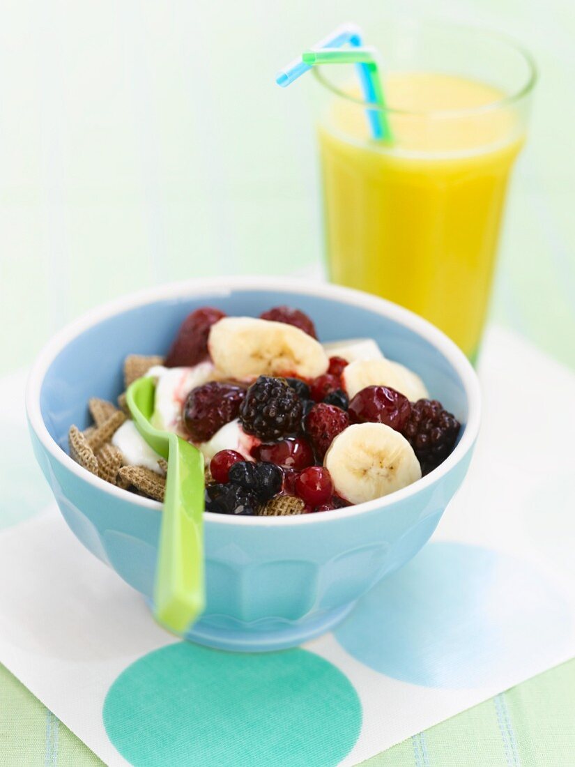 Cereals with berries and bananas and a glass of orange juice