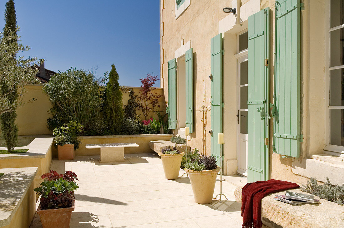 Sunny terrace with plant pots in front of a Mediterranean home