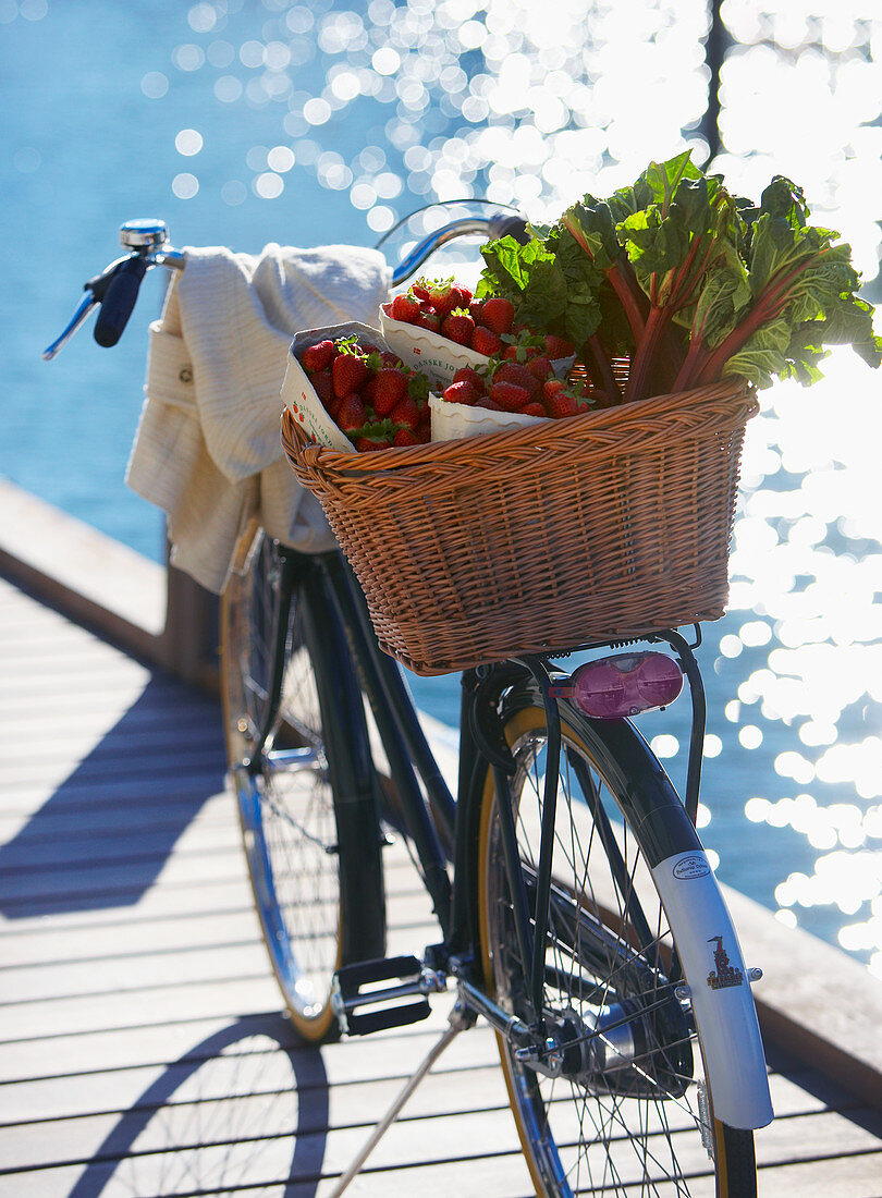 Fresh strawberries and rhubarb in a bicycle basket