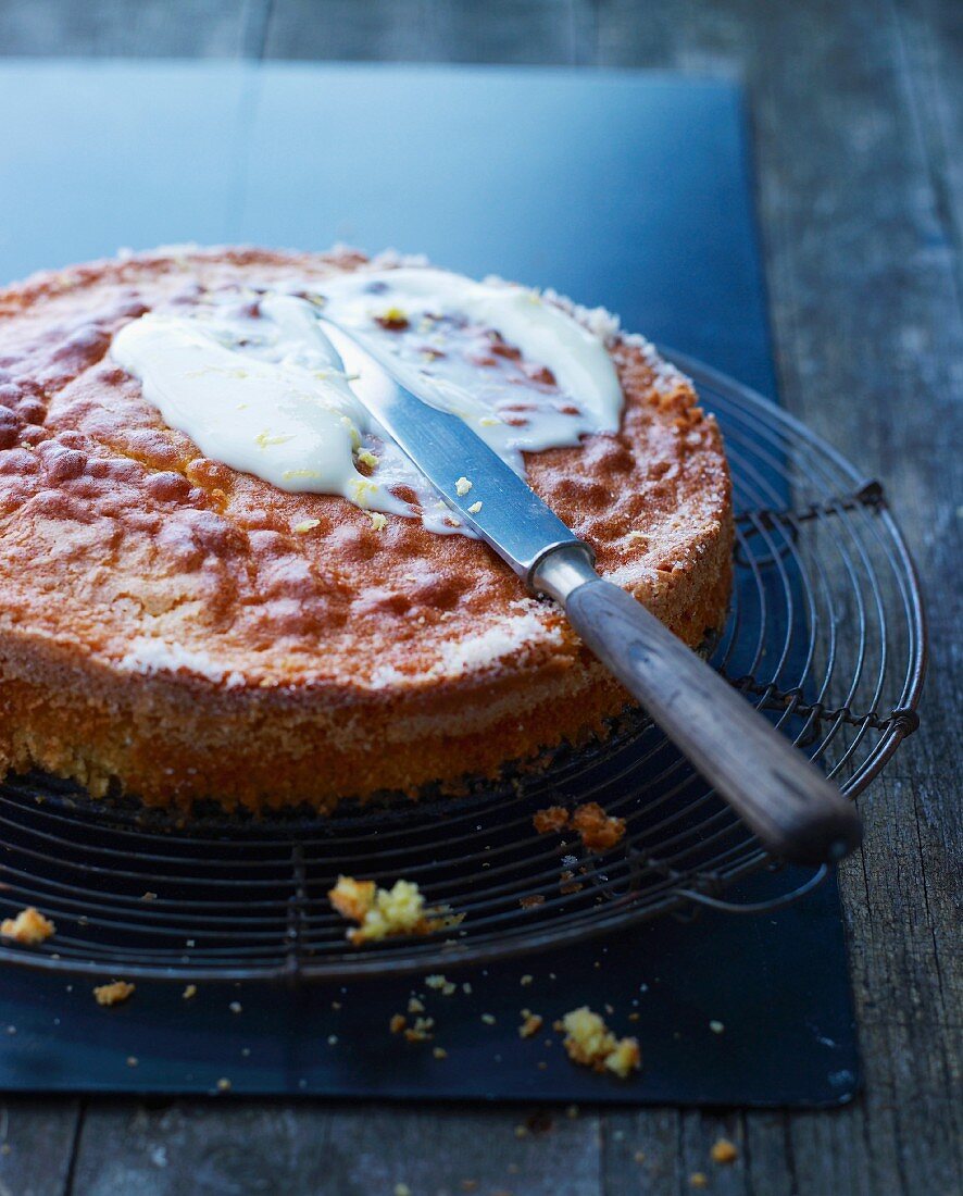 A cake being spread with lemon glaze