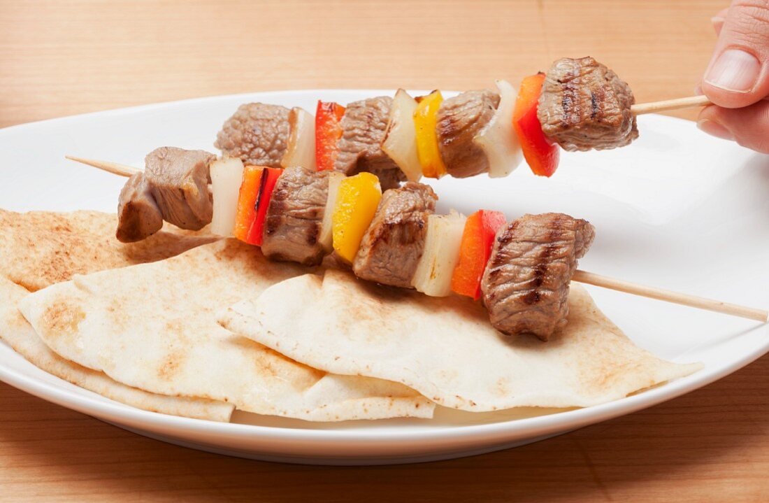 Grilled meat and vegetable kebabs on unleavened bread