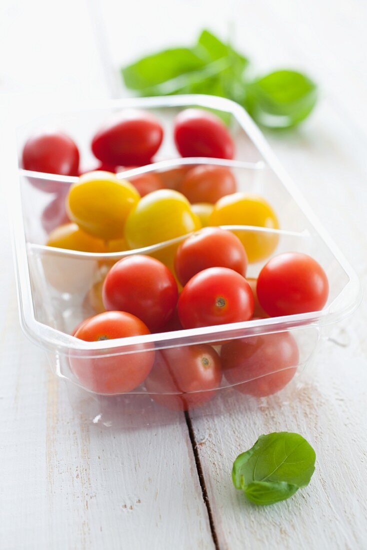 Cherry tomatoes in a plastic container with basil