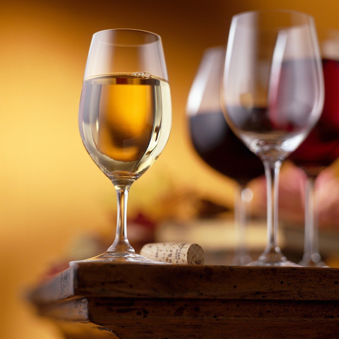 Glass of White Wine on a Table with Wine Cork, Wine Glasses and Glass of Red Wine