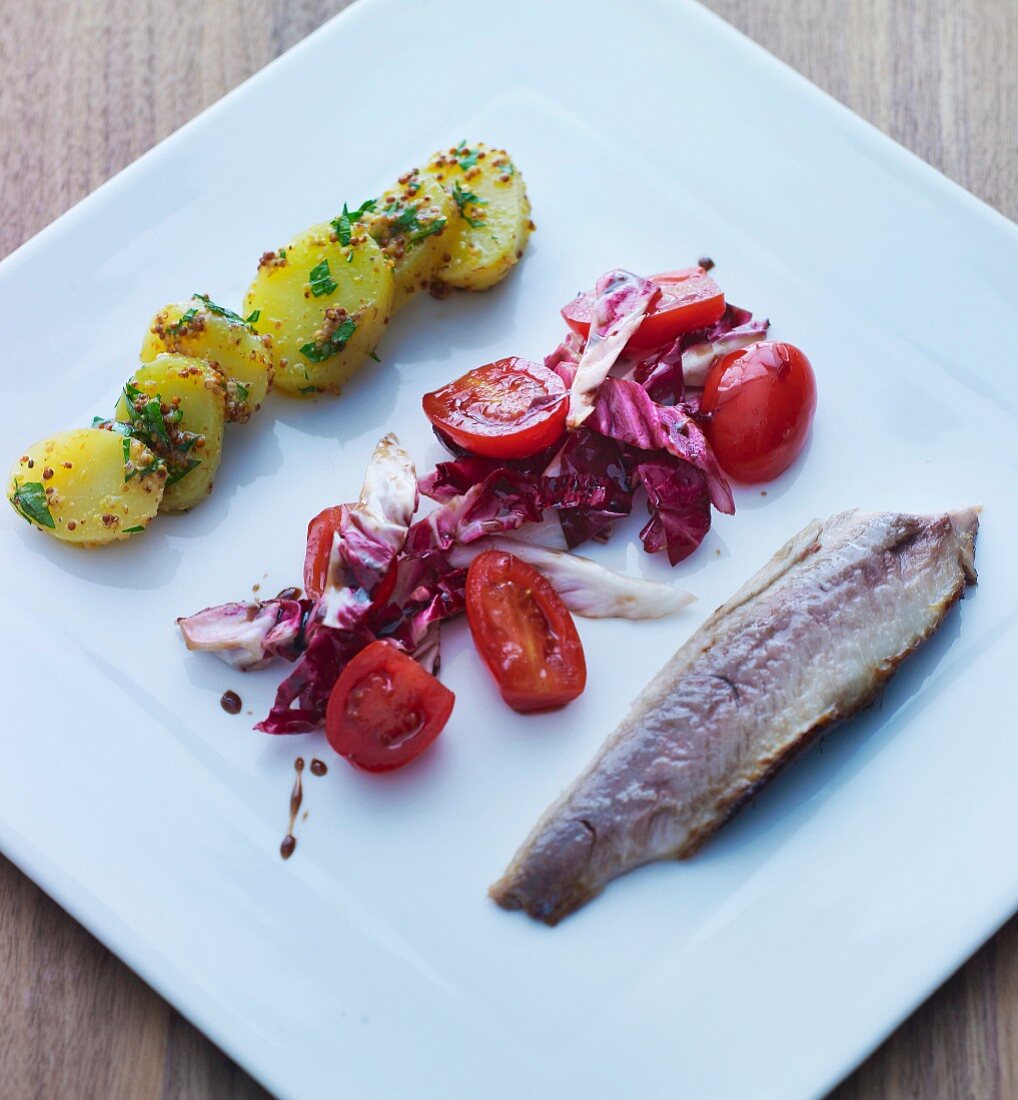 A herring fillet, tomato salad and potatoes (Scandinavia)