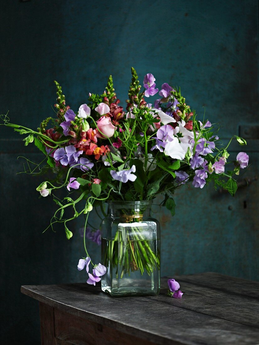 Wickenstrauss in Vase auf Holztisch