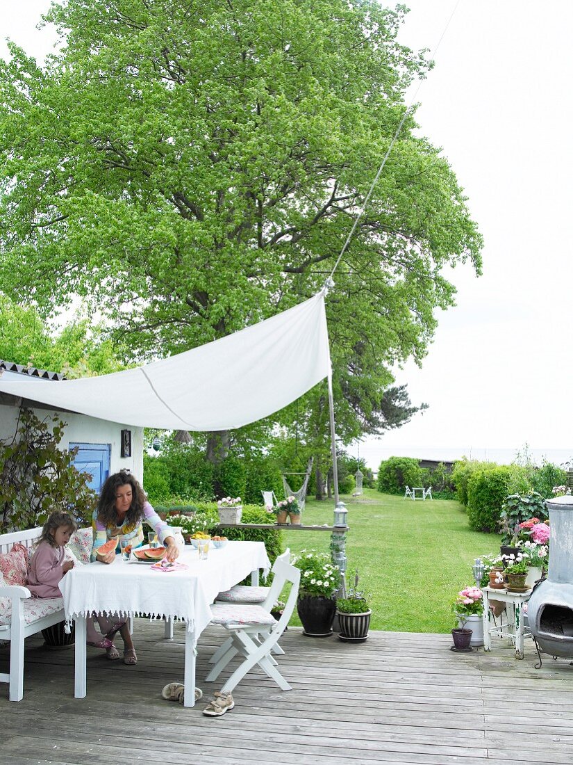 Mother and child below awning on terrace in spacious garden