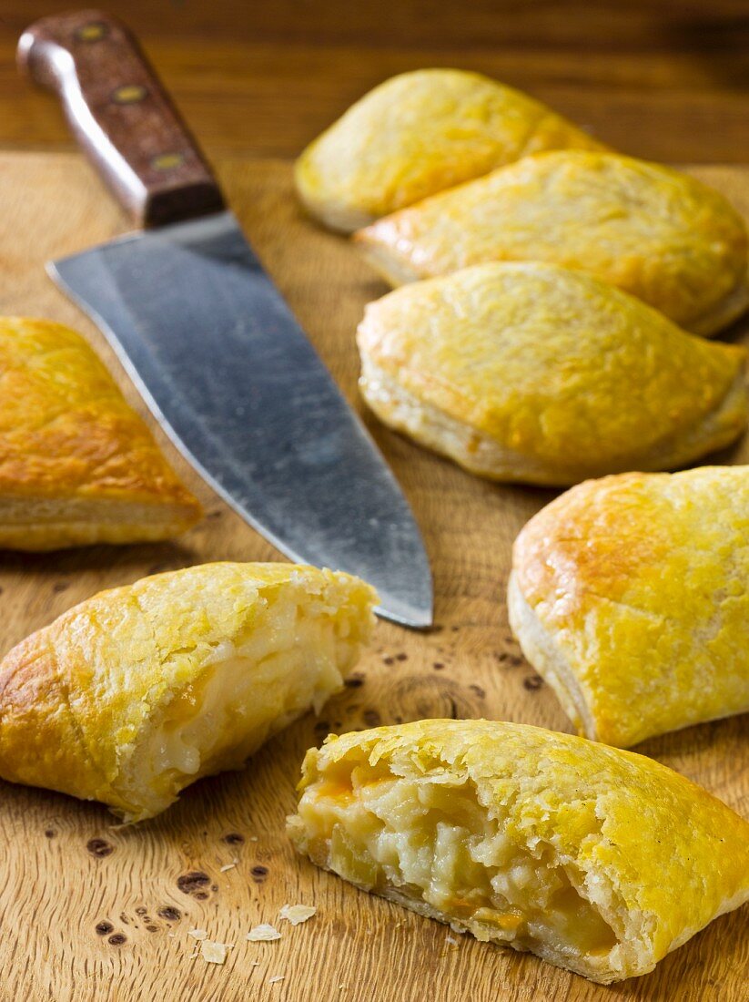 Mini cheese and onion pasties on a wooden board