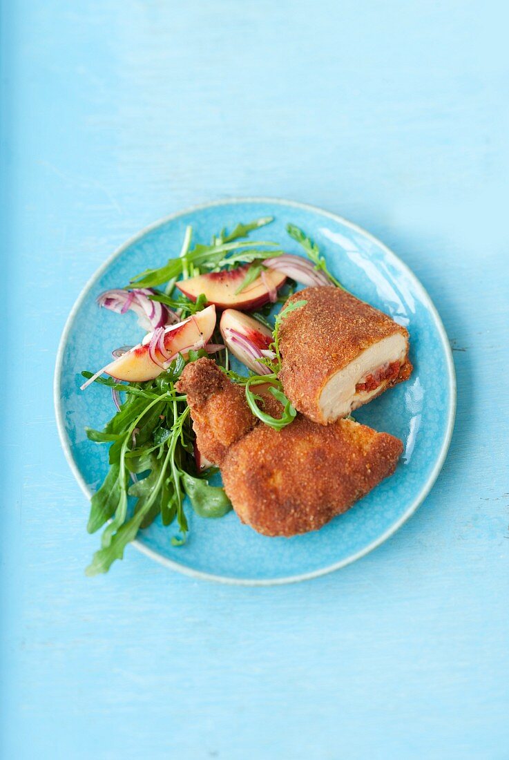Fried chicken filled with camembert and sausage and a peach and rocket salad