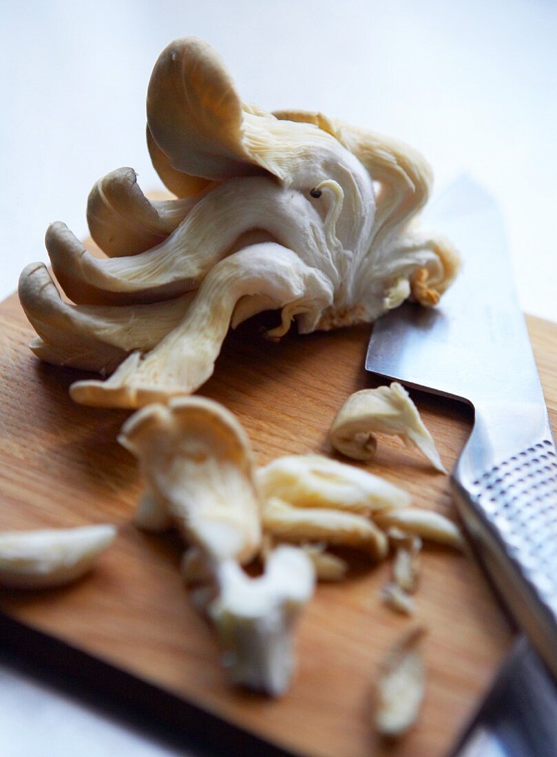 Oyster mushrooms on a chopping board with a knife