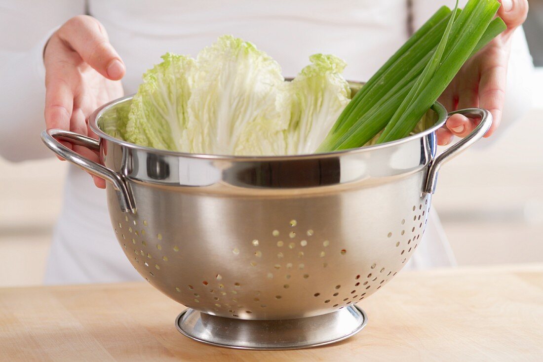 Spring onions and lettuce leaves in a colander
