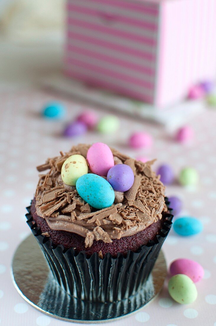 A red velvet cupcake with chocolate cream and sugar eggs