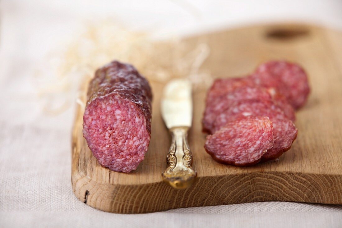 Salami, partially sliced, on a chopping board