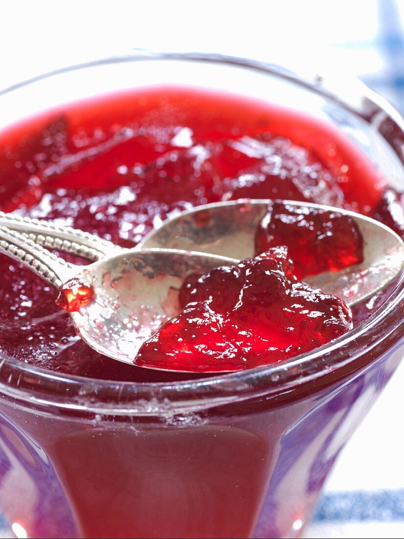 Redcurrant jelly in a glass with silver spoons