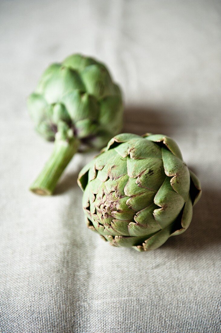 Two artichokes on a linen cloth