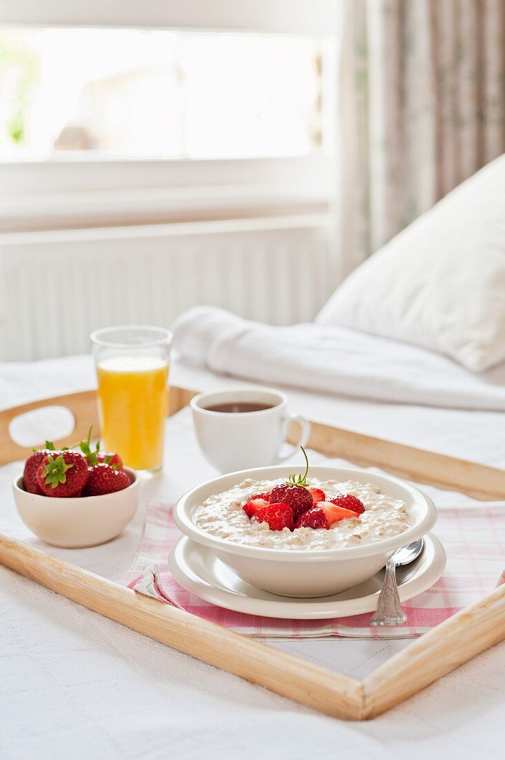 Frühstückstablett im Bett (Porridge mit Erdbeeren, Kaffee, Orangensaft)