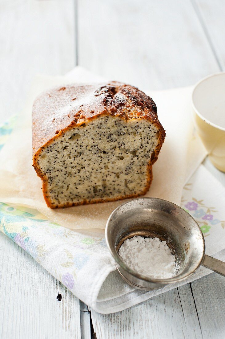 Lemon and poppy seed cake and icing sugar in a sieve