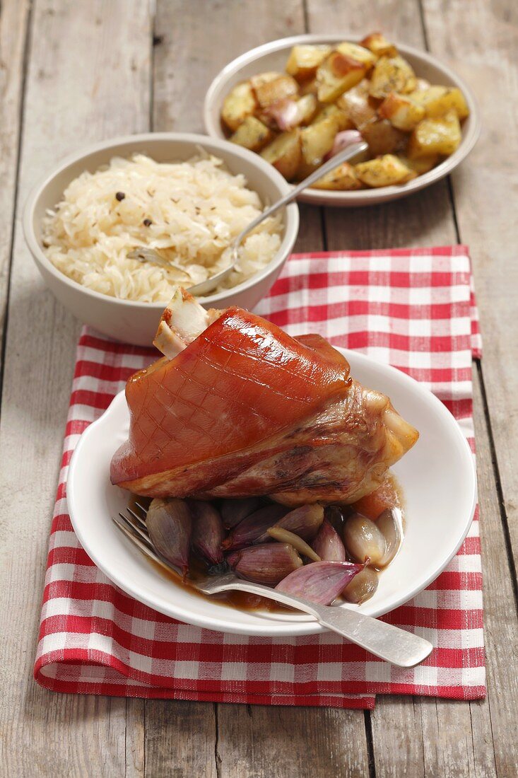 Schweinshaxe mit Schalotten, Bratkartoffeln und Sauerkraut