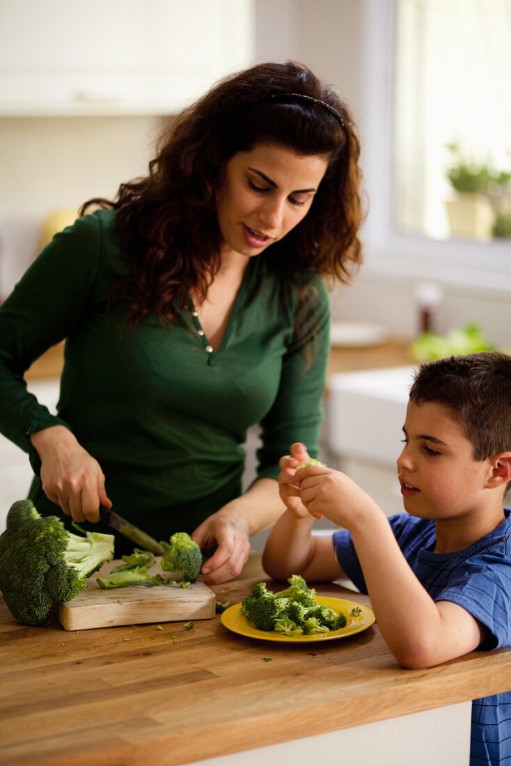 Mutter und Sohn zerkleinern Brokkoli in der Küche