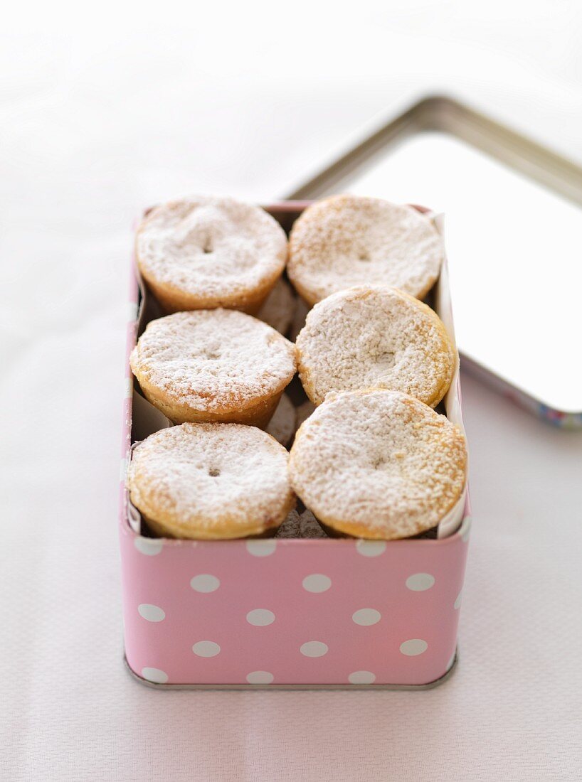 Mince pies dusted with icing sugar in a tin