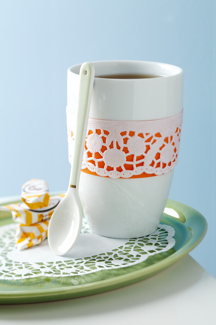 A cup decorated with a doily on a plate