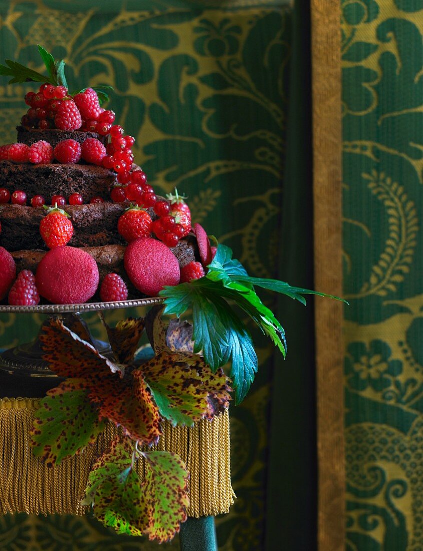 Mehrstöckige Schokoladentorte mit frischen roten Beeren und Keksen dekoriert