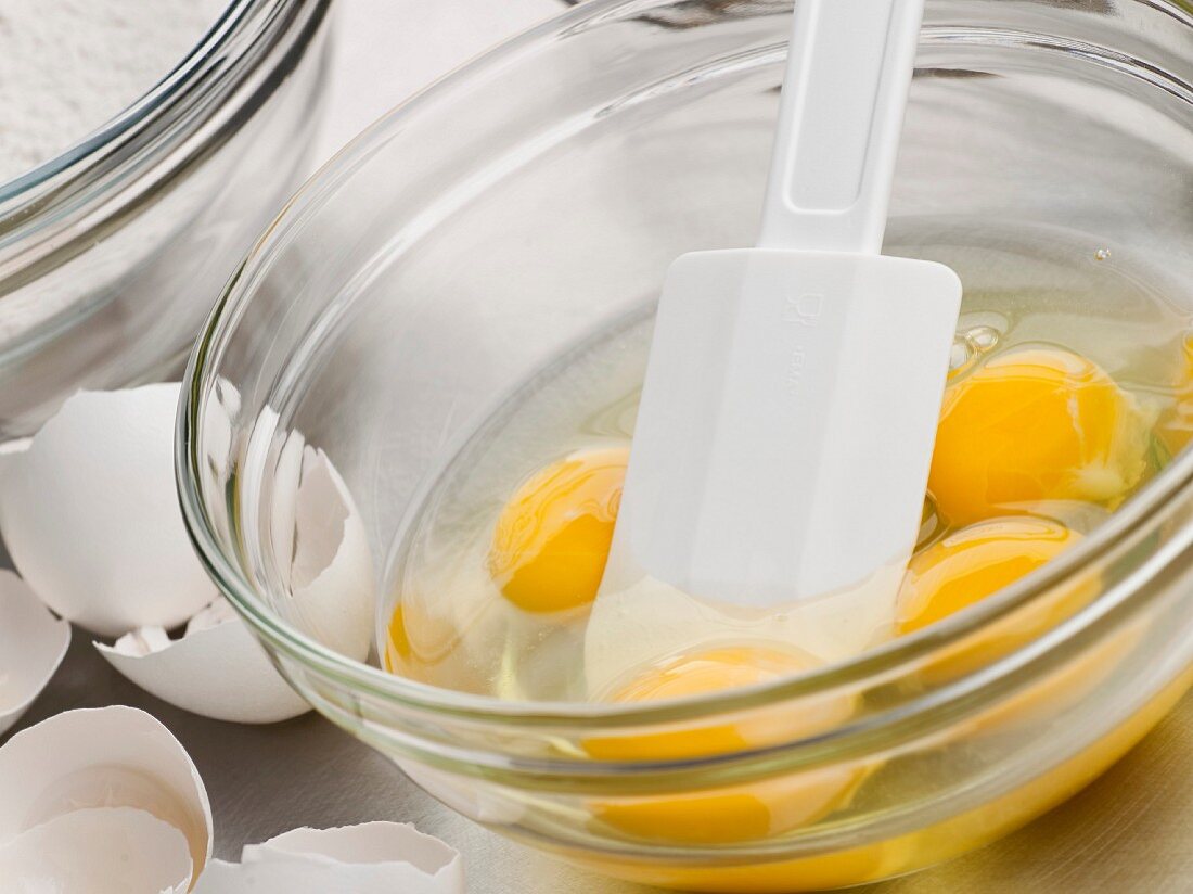 Cracked Eggs in a Mixing Bowl with a Rubber Spatula