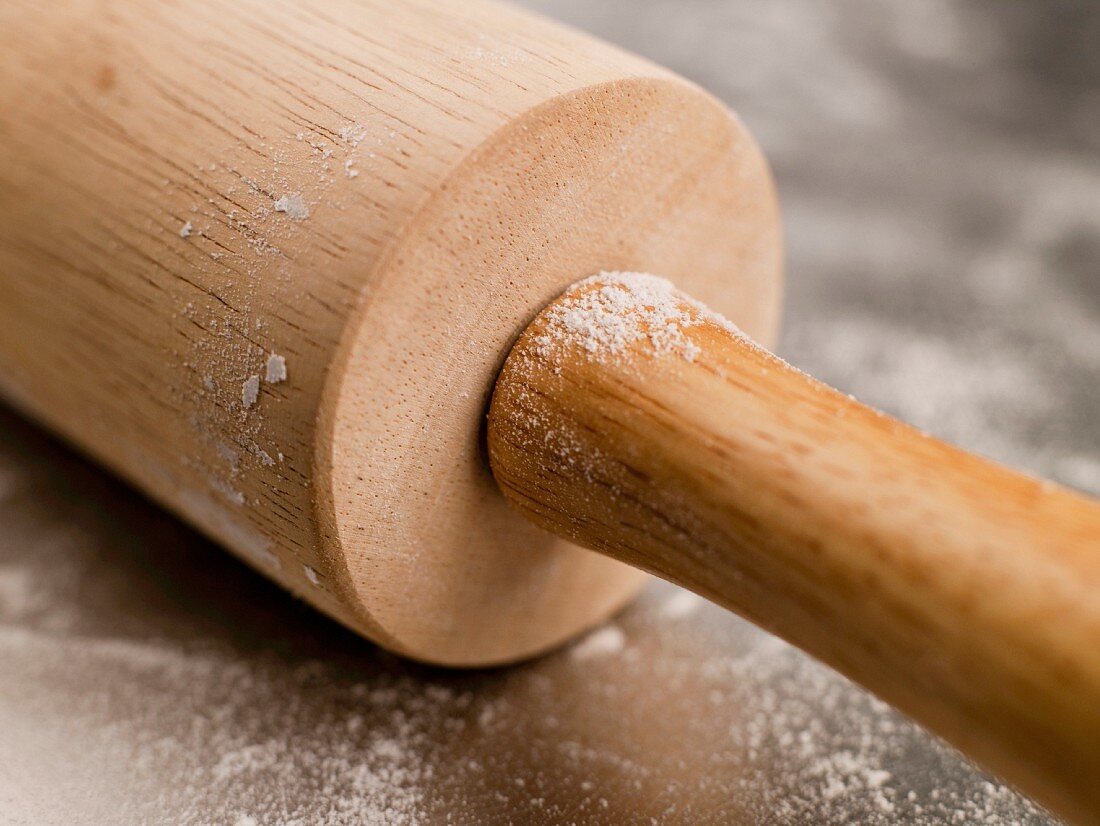 Wooden Rolling Pin with Flour on a Steel Surface